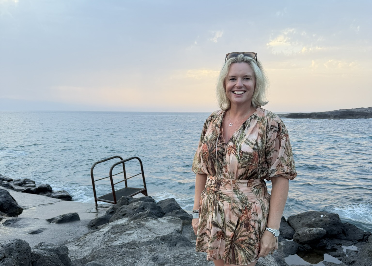 Erica smiling on a rocky coastline at sunset